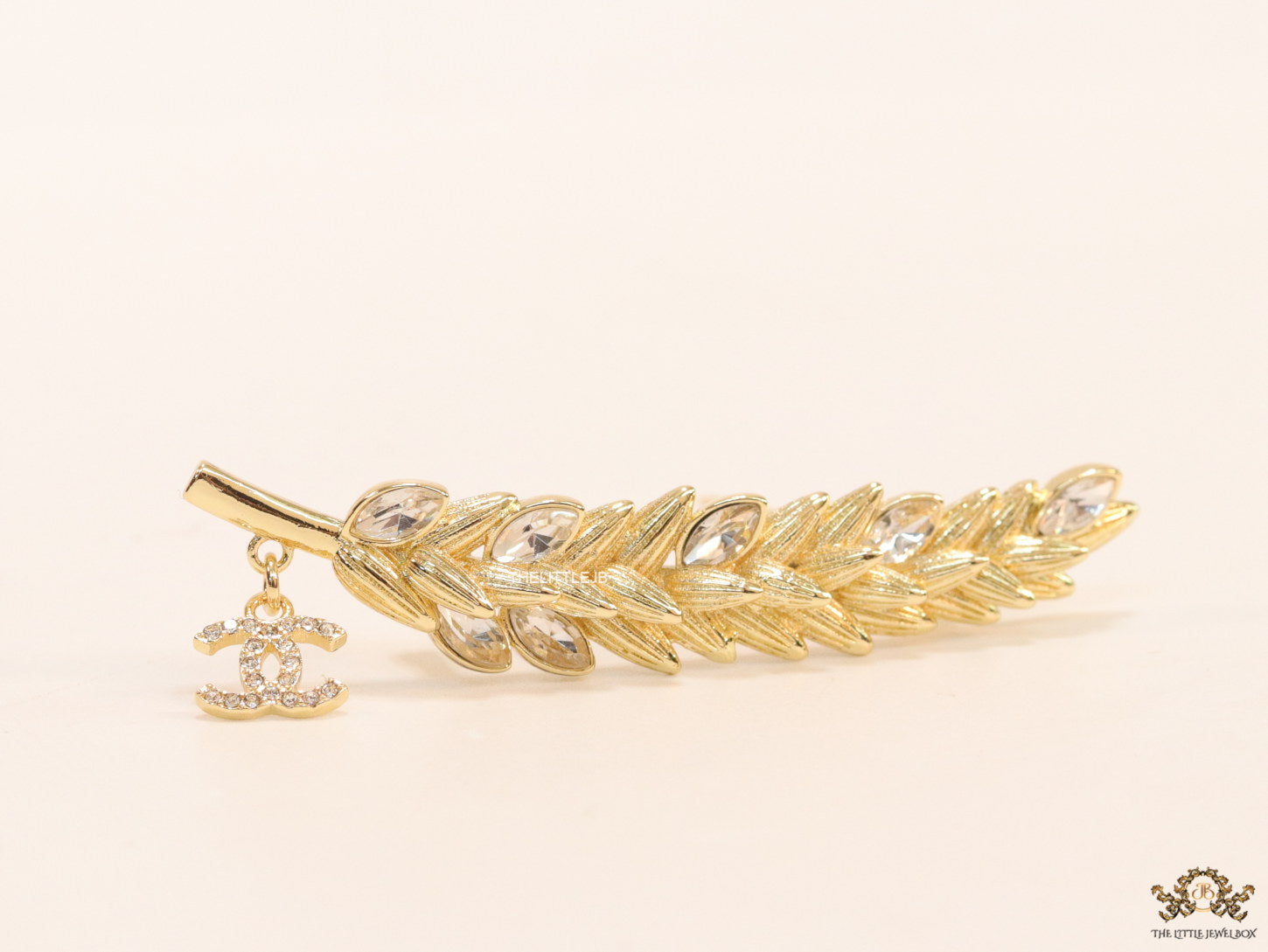 Golden feather brooch with fancy cz and twin C charm