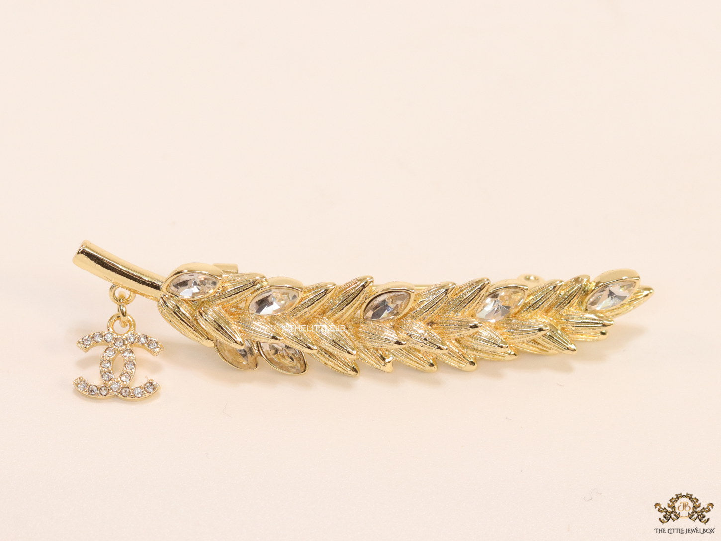 Golden feather brooch with fancy cz and twin C charm