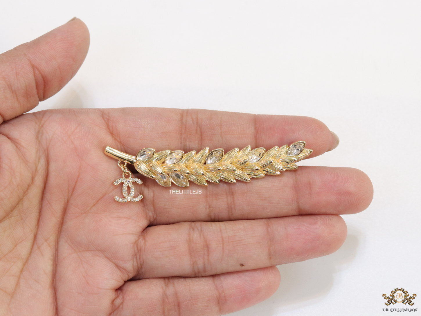 Golden feather brooch with fancy cz and twin C charm