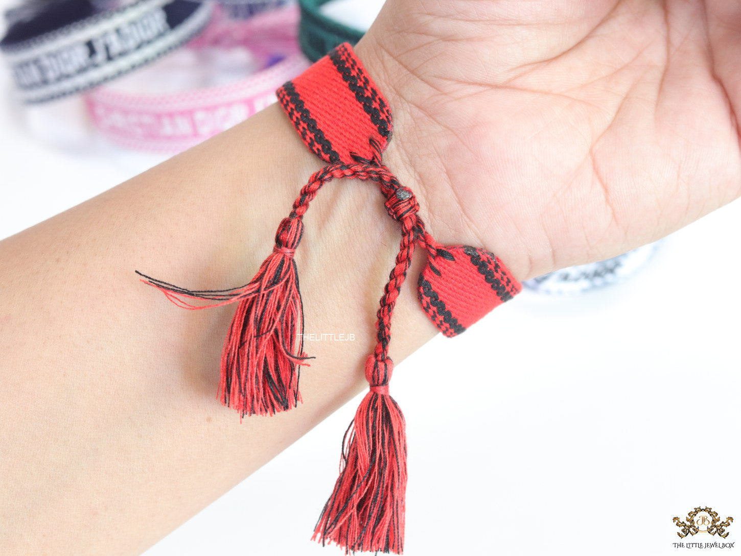 Adjustable red woven bracelet with black knitted alphabets and tassels
