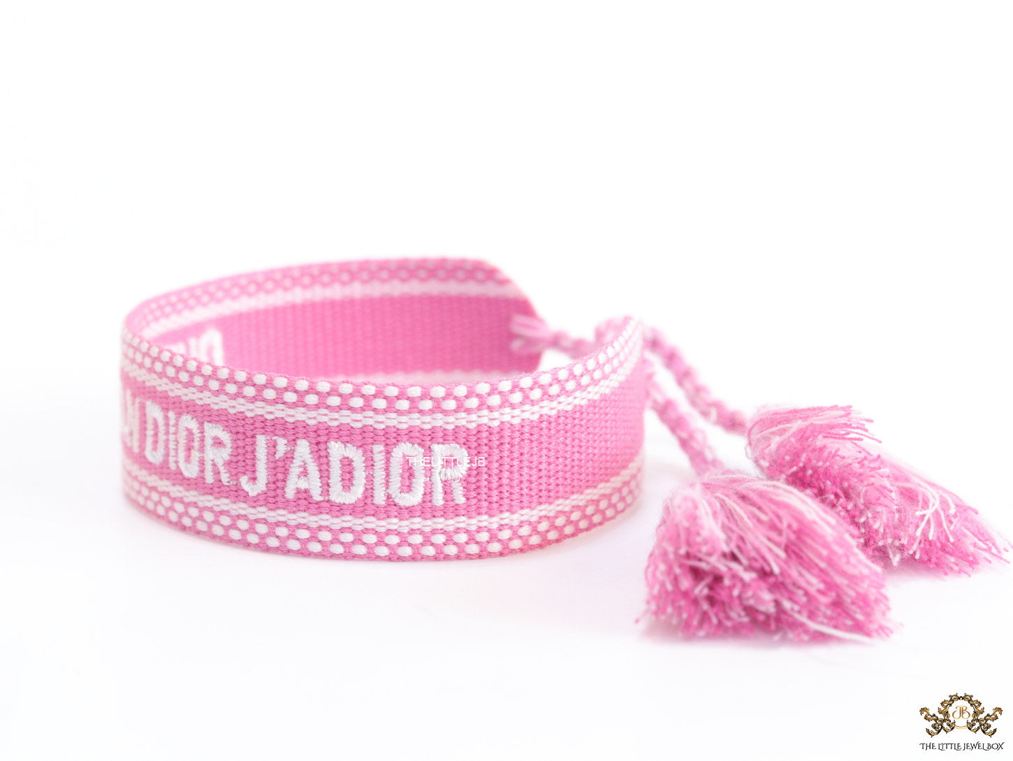 Adjustable pink woven bracelet with white knitted alphabets and tassels