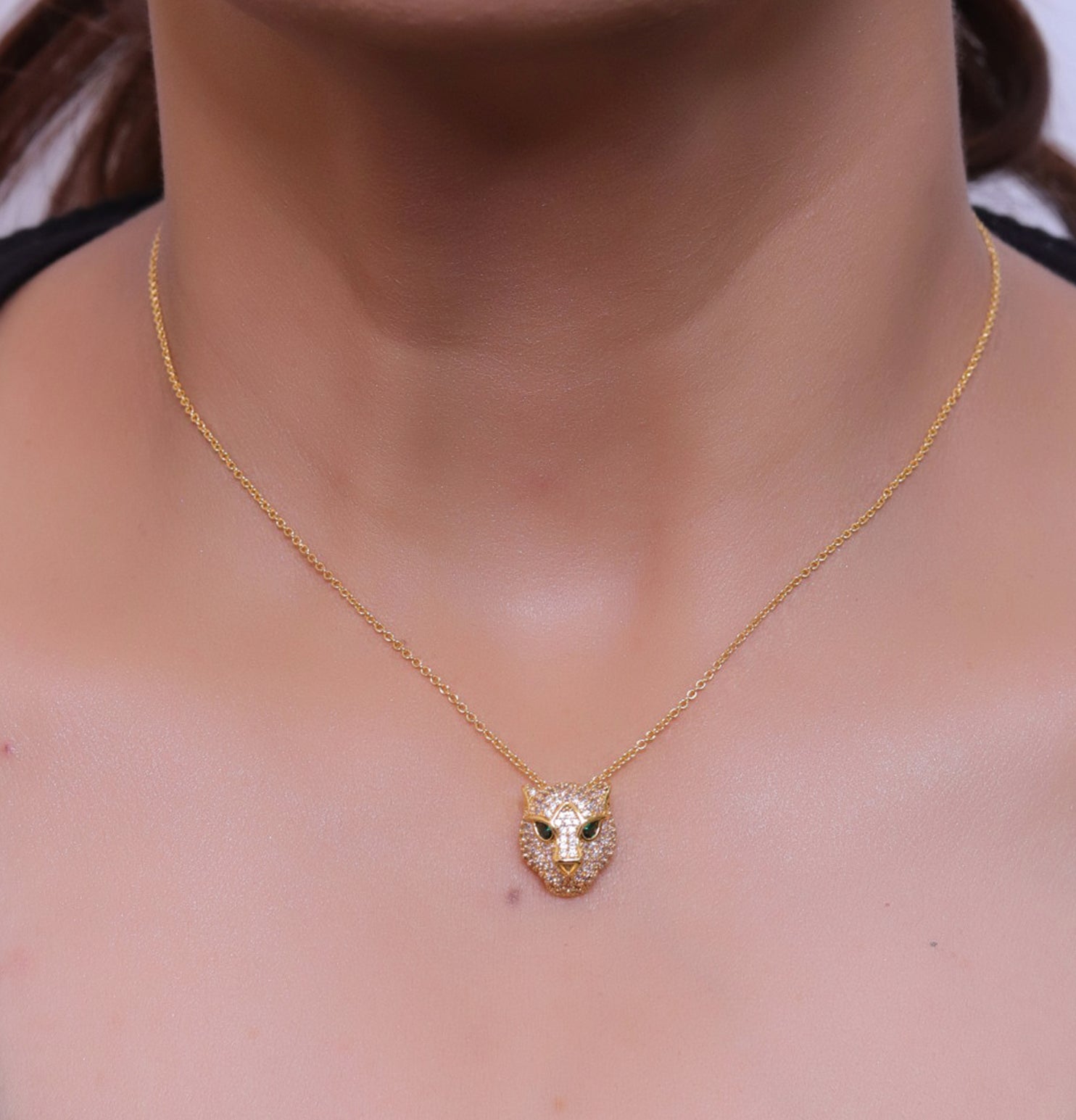Gold plated cubic zirconia stones panther face motif pendant with emerald green stones details on sleek gold plated chain