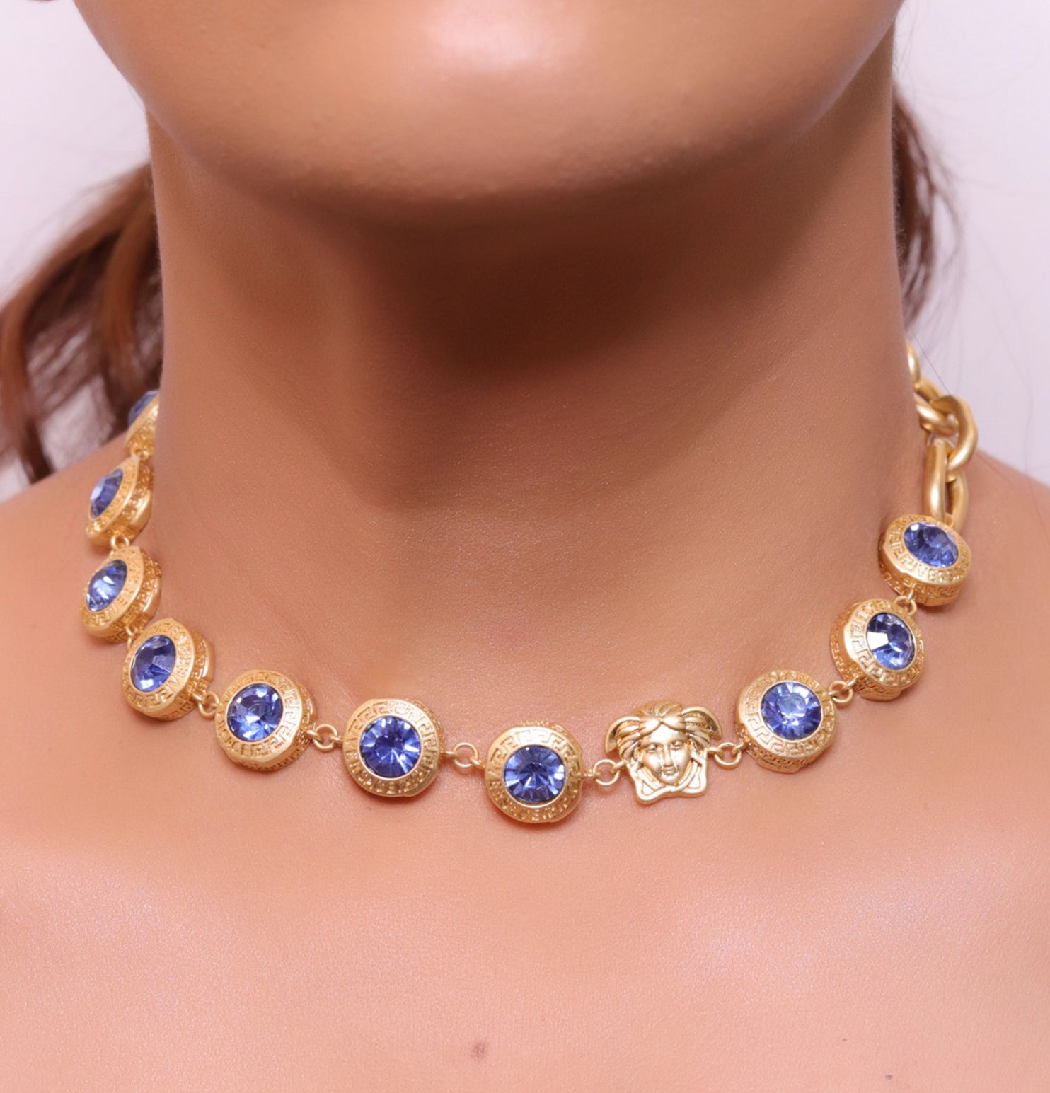 Gold plated link chain with blue cubic zirconia stones and gold plated Medusa motif charm.