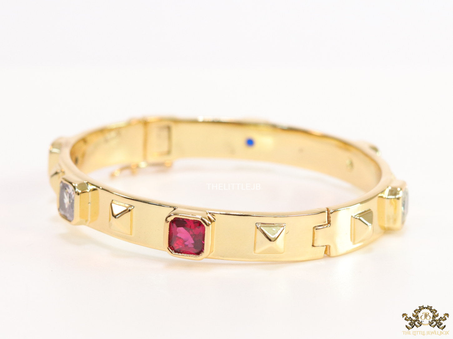 Band style bracelet in gold plating with gold plated details and ruby red colour stones