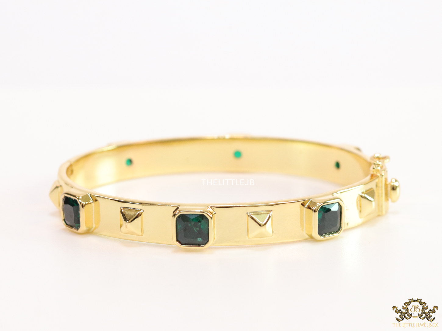 Band style bracelet in gold plating with gold plated details and emerald green colour stones