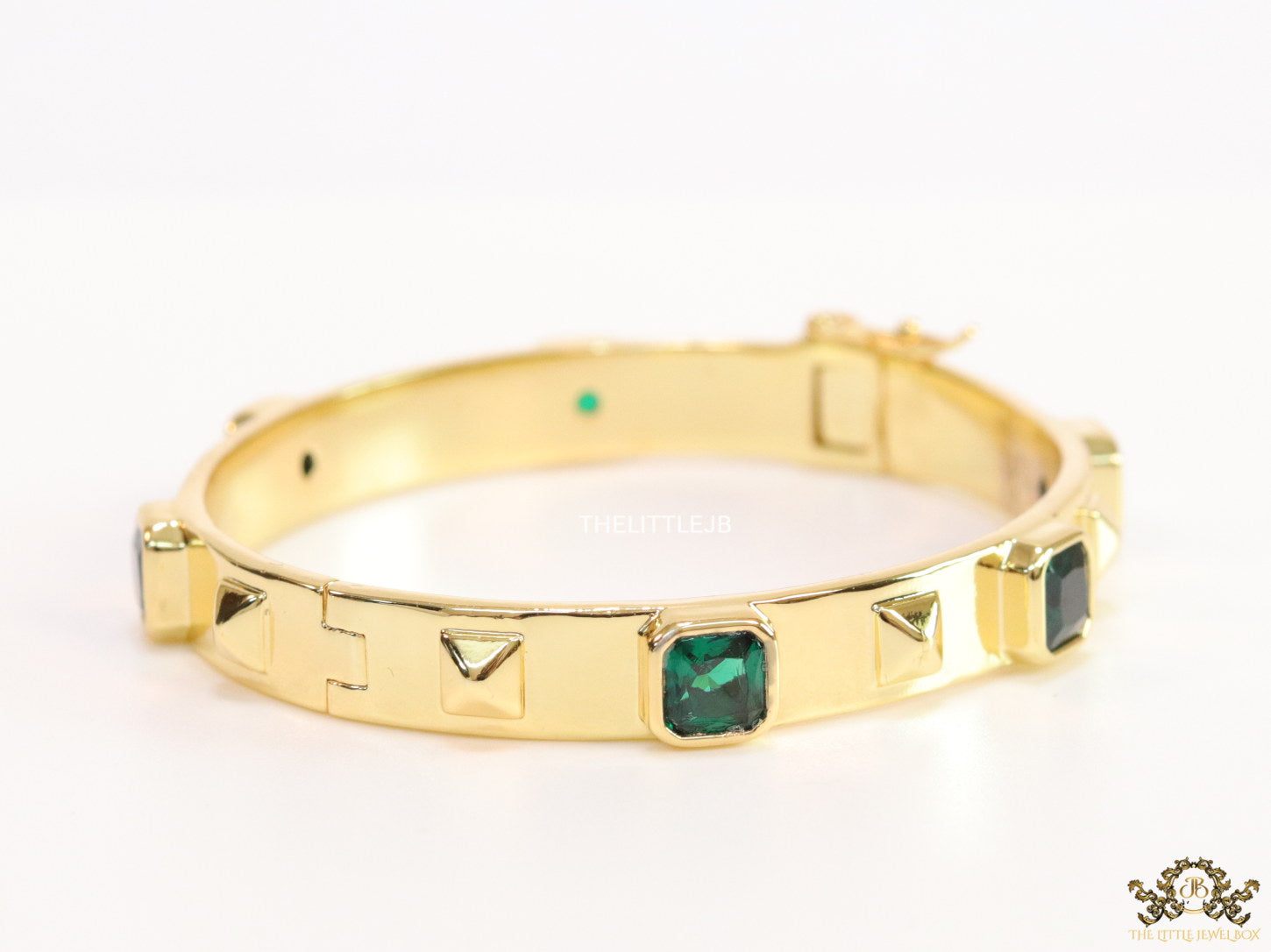 Band style bracelet in gold plating with gold plated details and emerald green colour stones