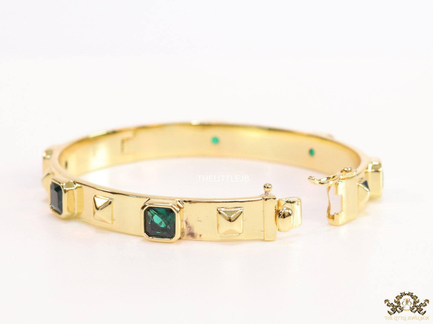 Band style bracelet in gold plating with gold plated details and emerald green colour stones