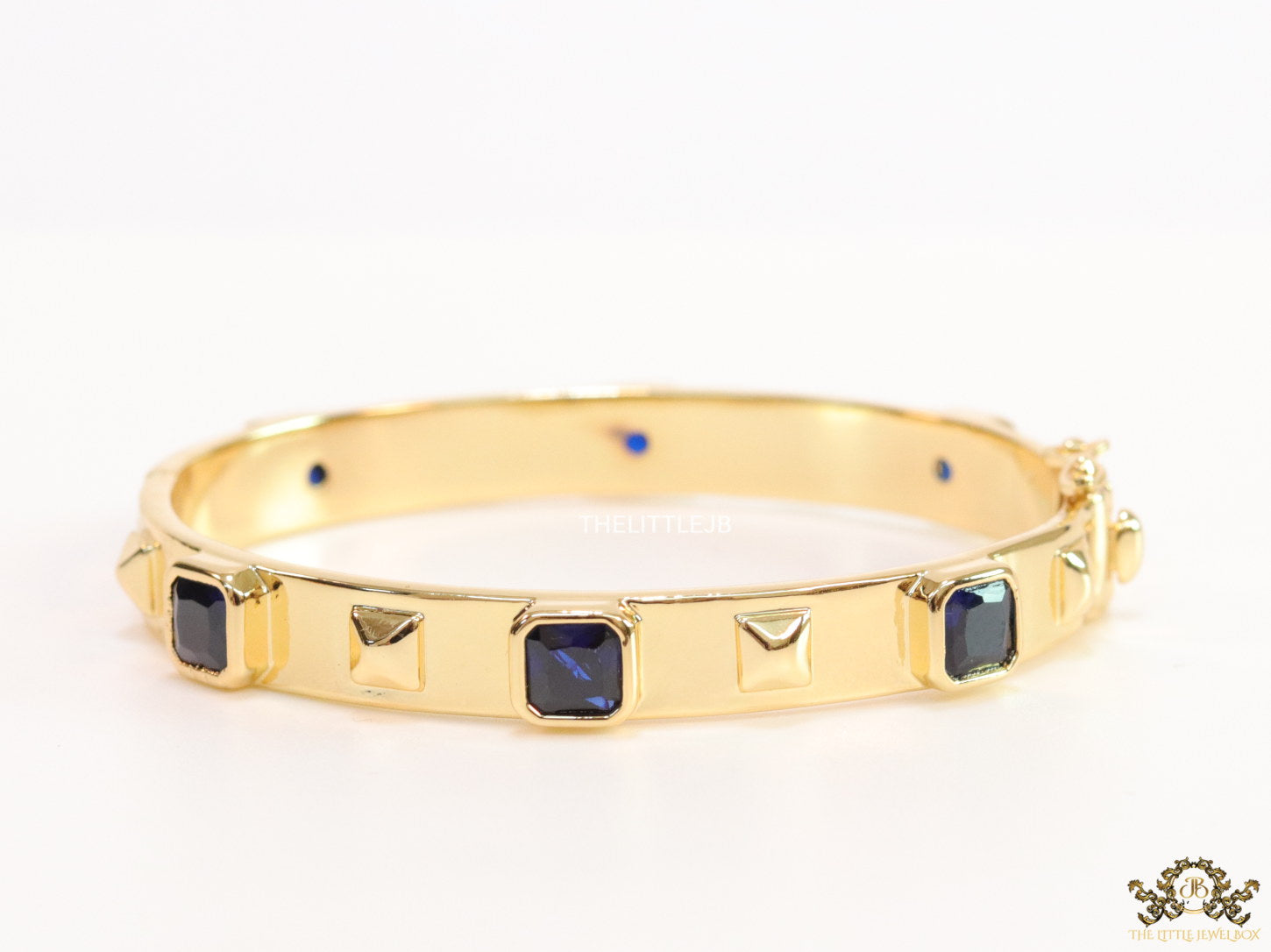 Band style bracelet in gold plating with gold plated details and sapphire blue colour stones