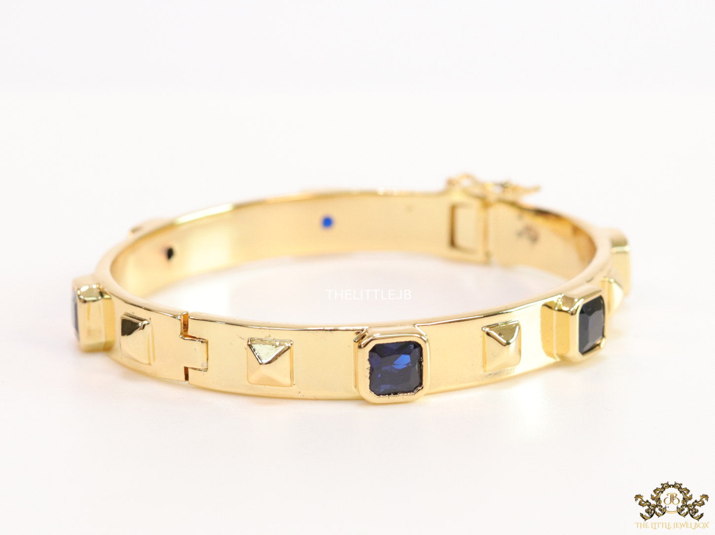 Band style bracelet in gold plating with gold plated details and sapphire blue colour stones