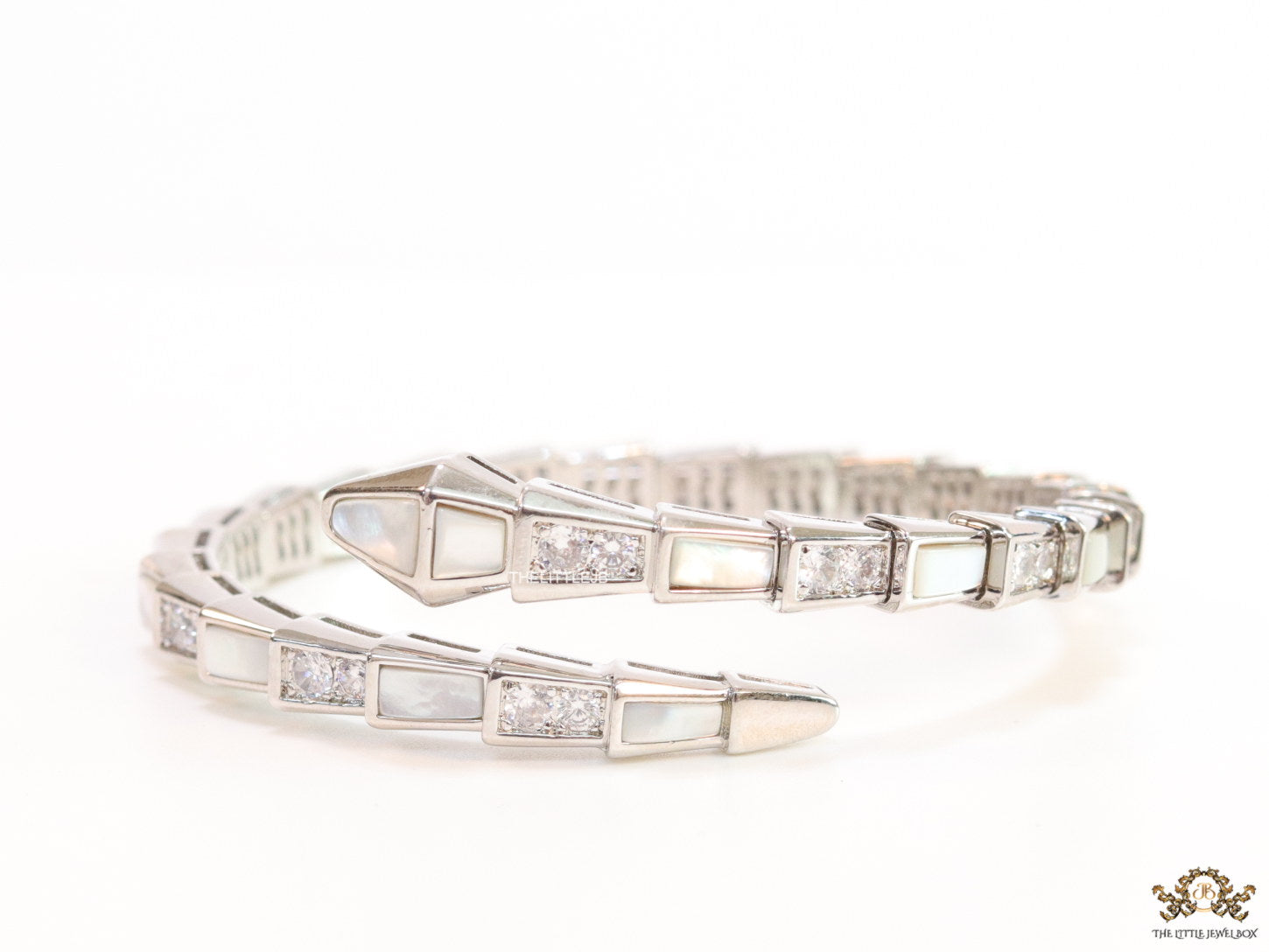 Open top platinum plated minimal serpentine bracelet with cubic zirconia stones and pearl white stones.