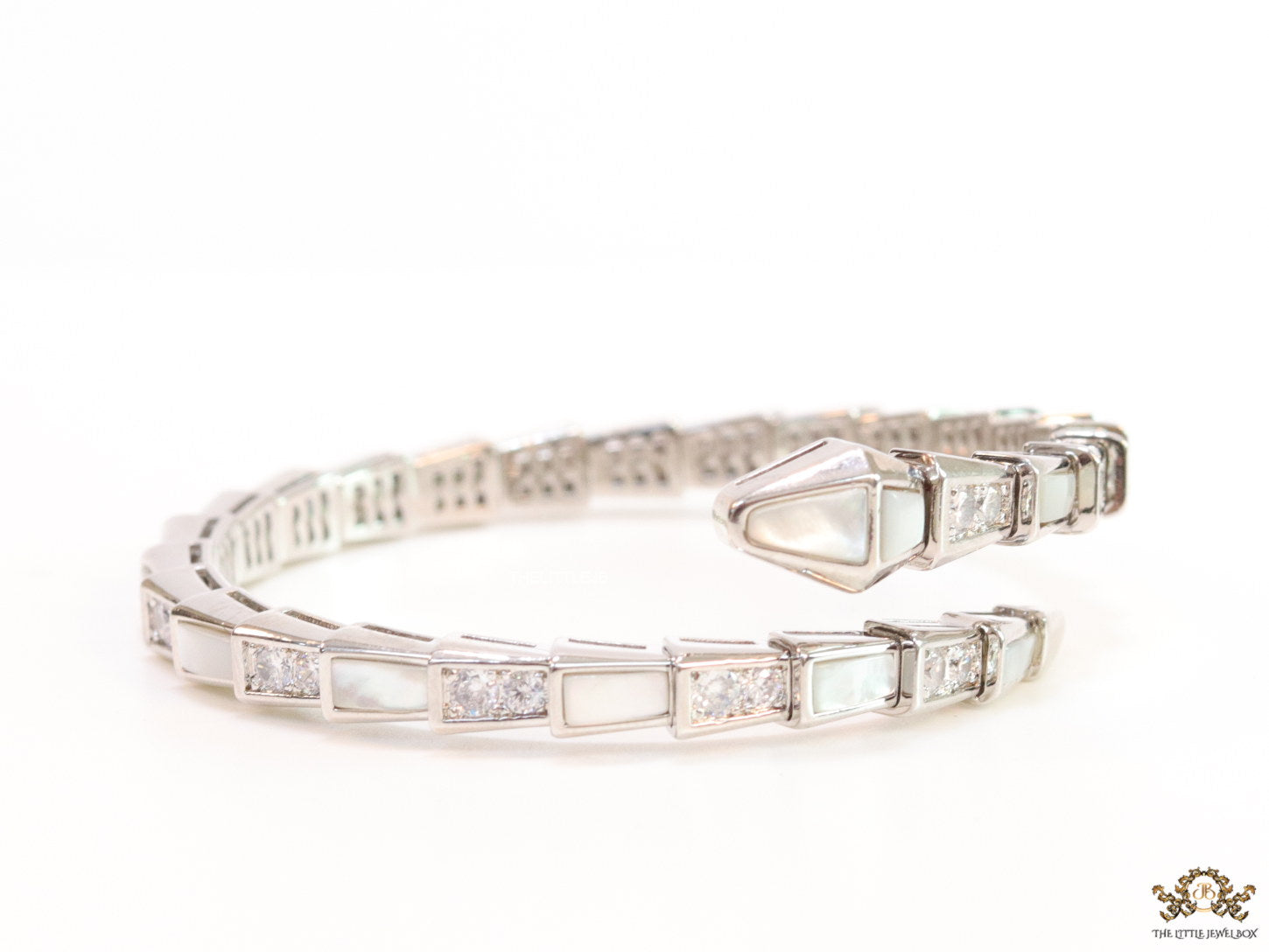 Open top platinum plated minimal serpentine bracelet with cubic zirconia stones and pearl white stones.