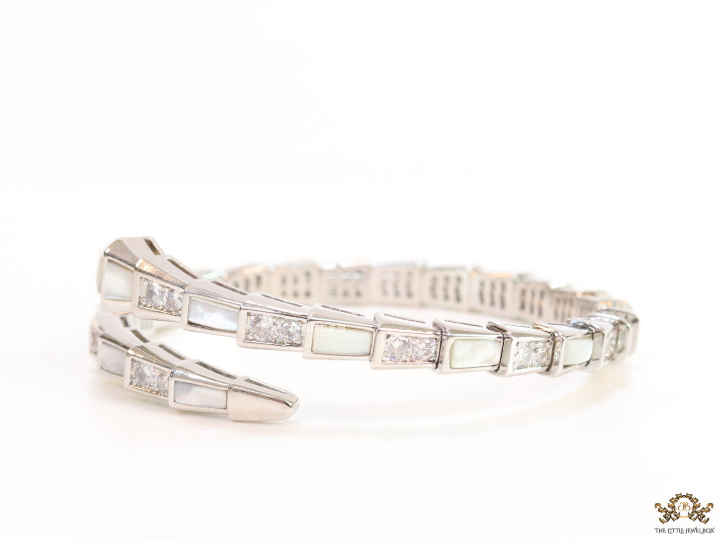 Open top platinum plated minimal serpentine bracelet with cubic zirconia stones and pearl white stones.