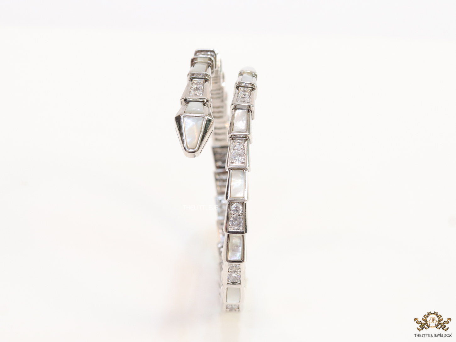 Open top platinum plated minimal serpentine bracelet with cubic zirconia stones and pearl white stones.