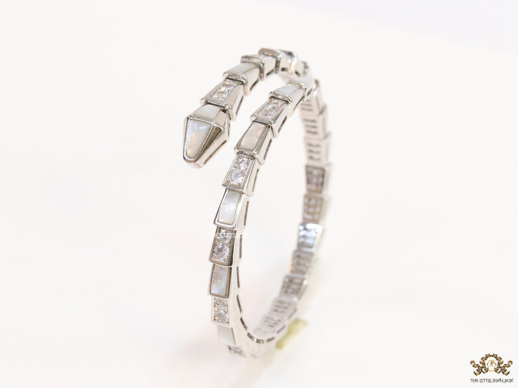 Open top platinum plated minimal serpentine bracelet with cubic zirconia stones and pearl white stones.