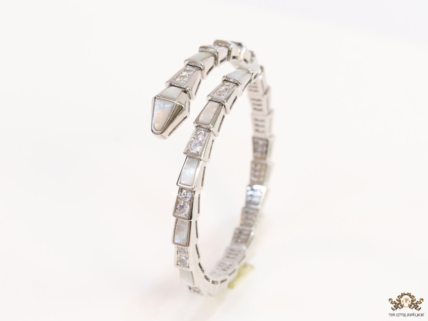 Open top platinum plated minimal serpentine bracelet with cubic zirconia stones and pearl white stones.