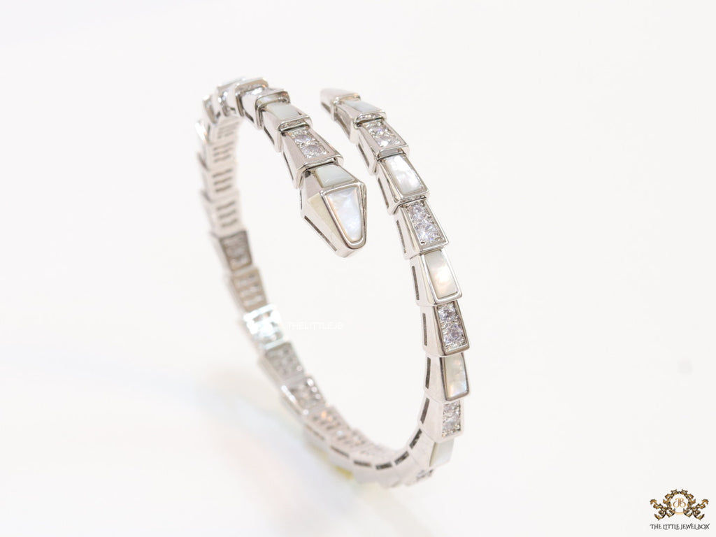 Open top platinum plated minimal serpentine bracelet with cubic zirconia stones and pearl white stones.