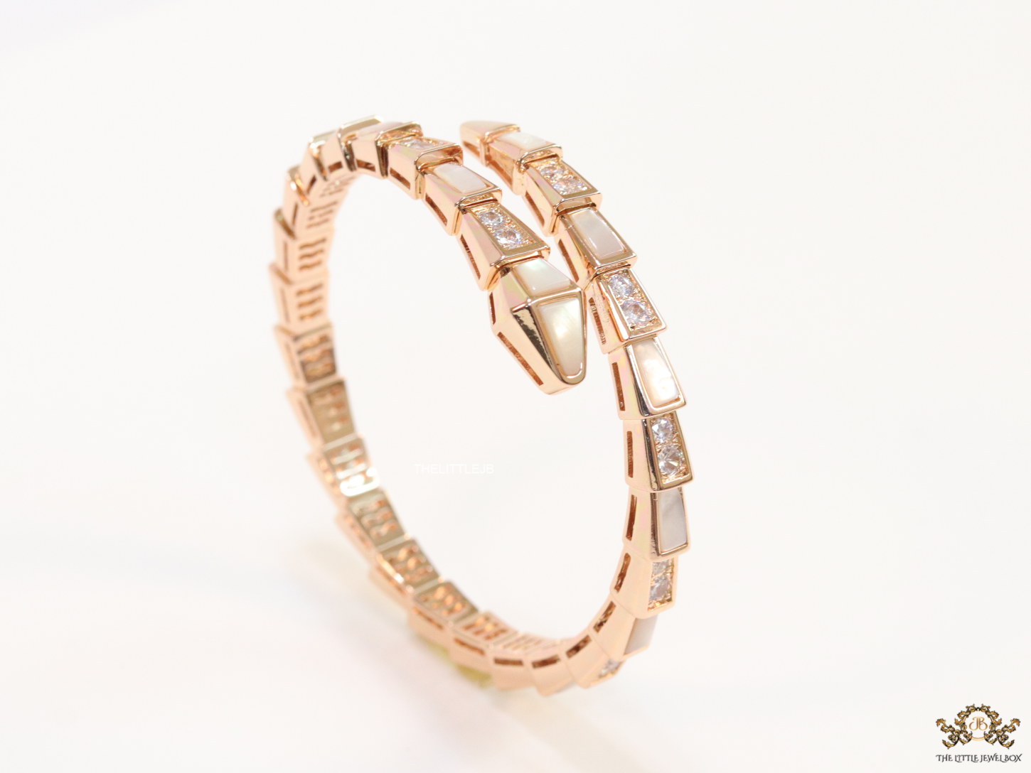 Open top rose gold plated minimal serpentine bracelet with cubic zirconia stones and pearl white stones.