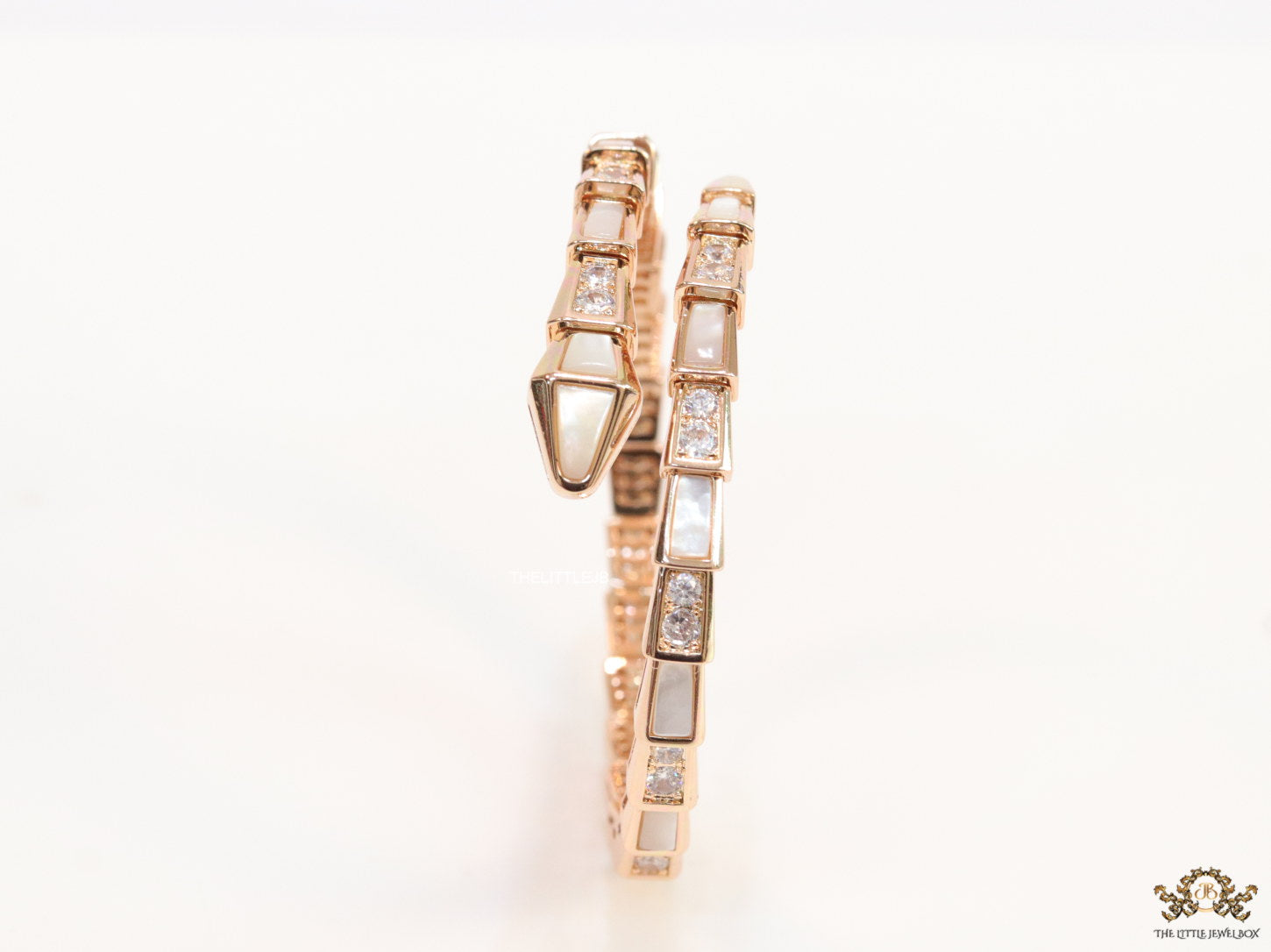 Open top rose gold plated minimal serpentine bracelet with cubic zirconia stones and pearl white stones.