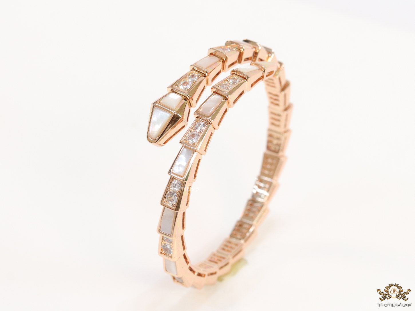 Open top rose gold plated minimal serpentine bracelet with cubic zirconia stones and pearl white stones.