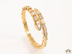 Open top gold plated minimal serpentine bracelet with cubic zirconia stones and pearl white stones.
