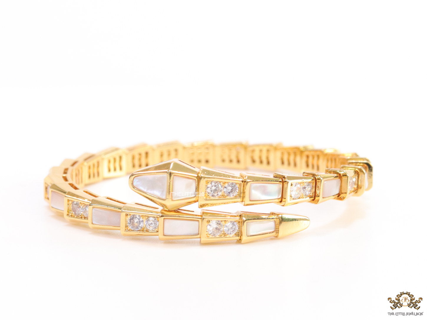 Open top gold plated minimal serpentine bracelet with cubic zirconia stones and pearl white stones.