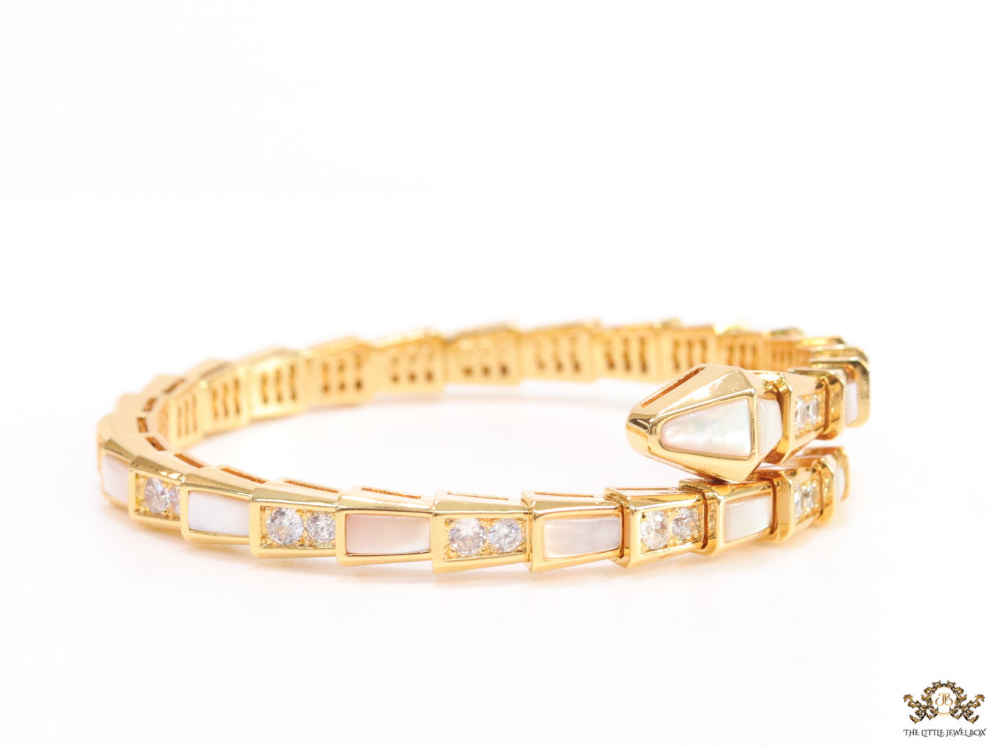 Open top gold plated minimal serpentine bracelet with cubic zirconia stones and pearl white stones.