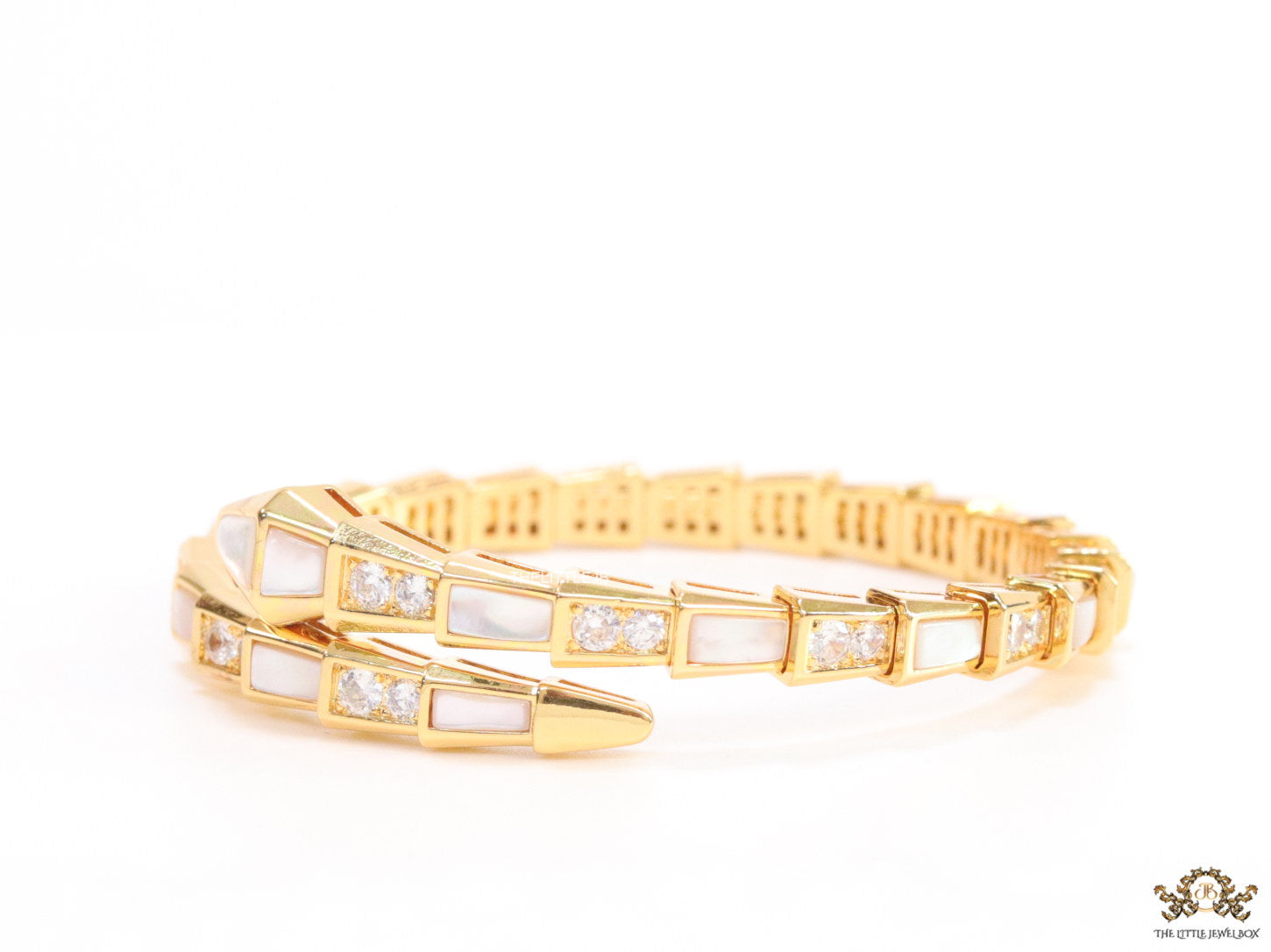 Open top gold plated minimal serpentine bracelet with cubic zirconia stones and pearl white stones.