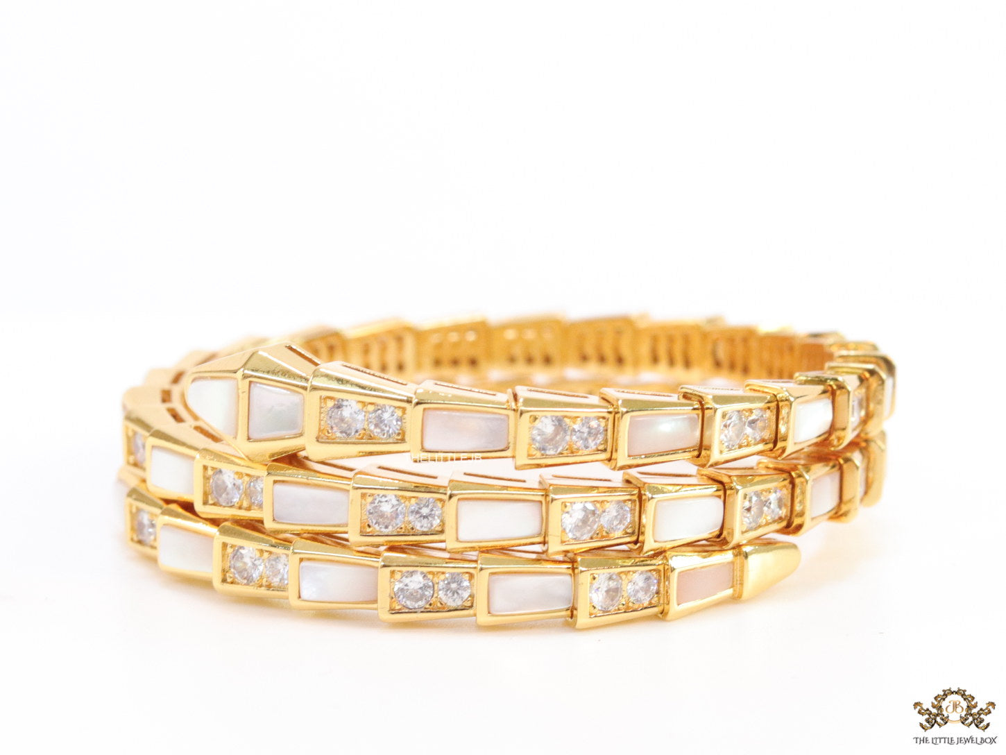 Triple line gold plated minimal serpentine bracelet with cubic zirconia stones and pearl white stones.