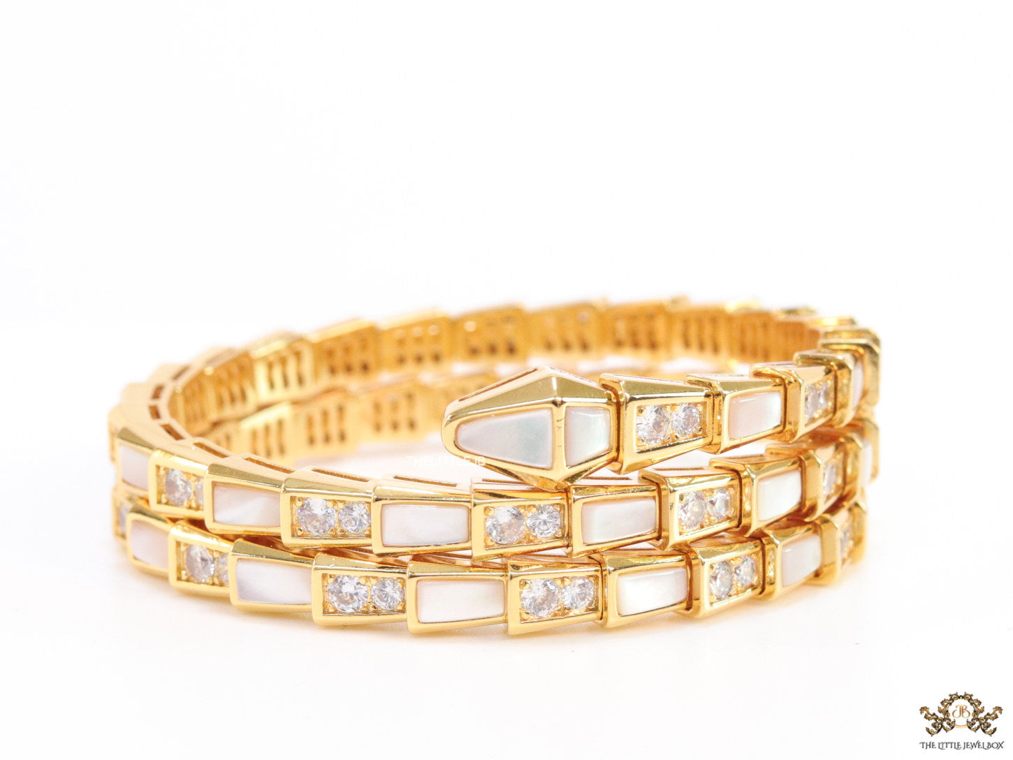 Triple line gold plated minimal serpentine bracelet with cubic zirconia stones and pearl white stones.