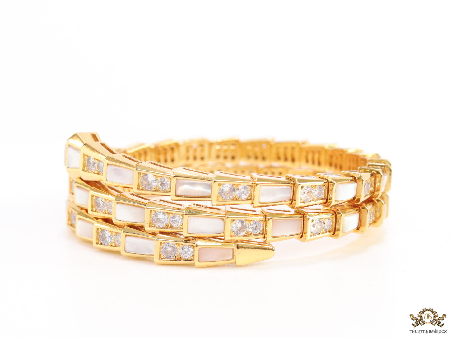 Triple line gold plated minimal serpentine bracelet with cubic zirconia stones and pearl white stones.