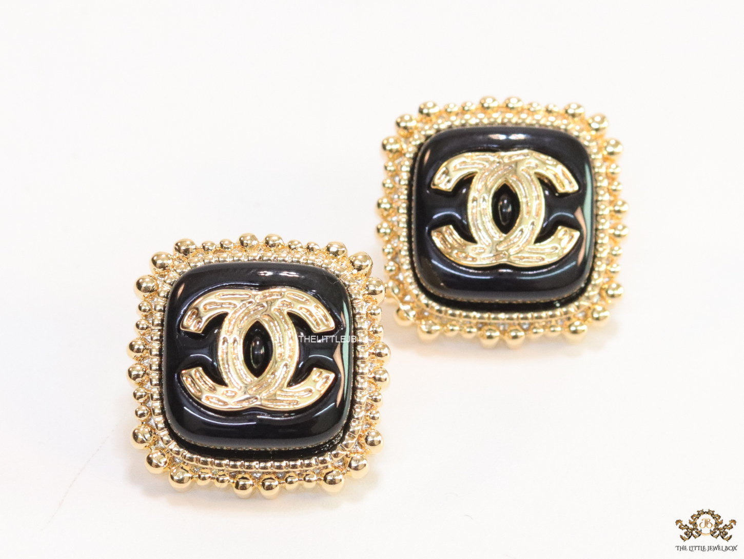 Square black and golden stud earrings with golden twin C motifs
