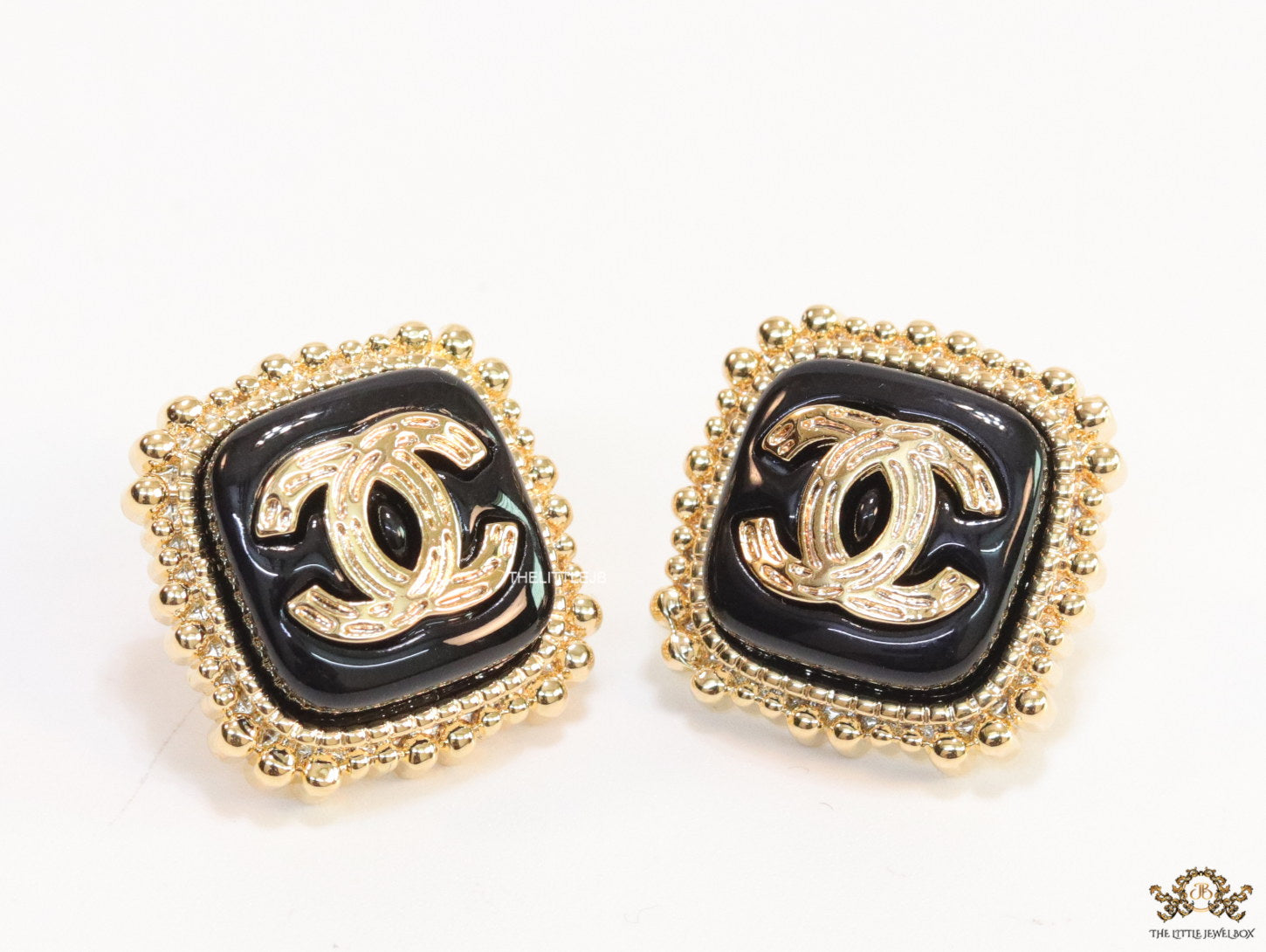 Square black and golden stud earrings with golden twin C motifs