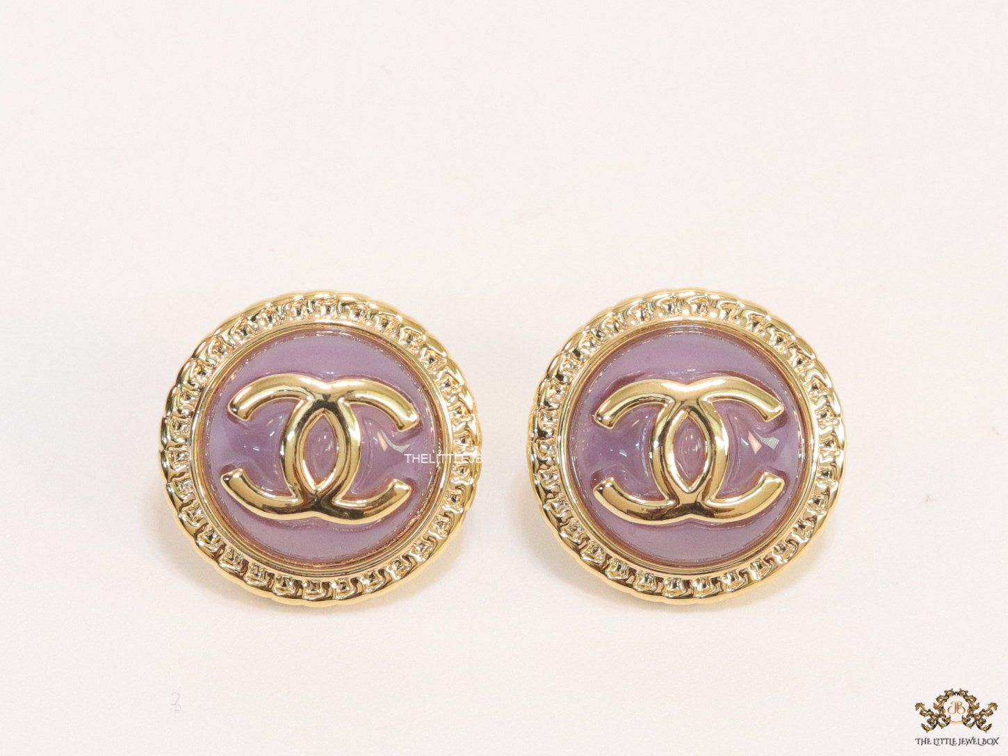 Twin C motif gold plated round studs on lilac acrylic base