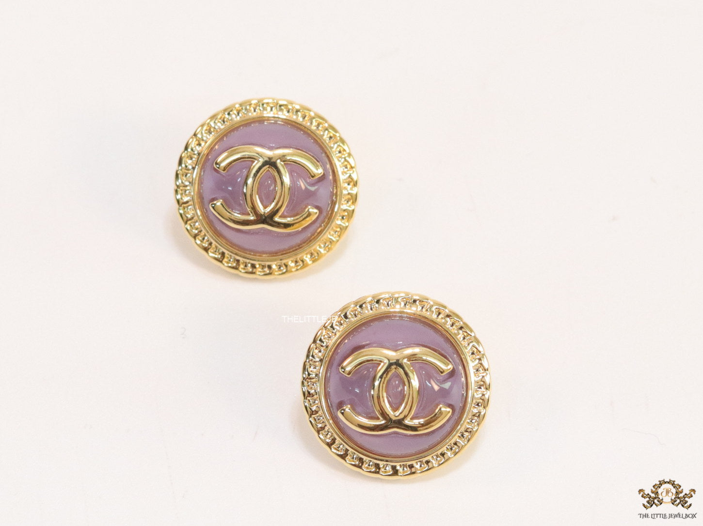 Twin C motif gold plated round studs on lilac acrylic base