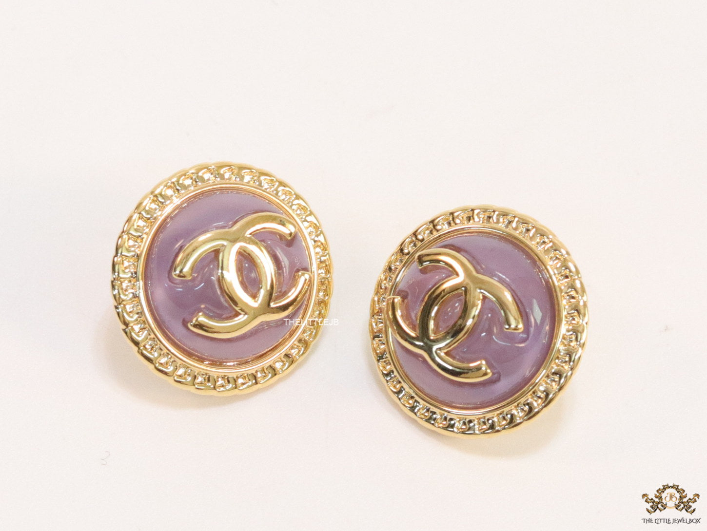 Twin C motif gold plated round studs on lilac acrylic base