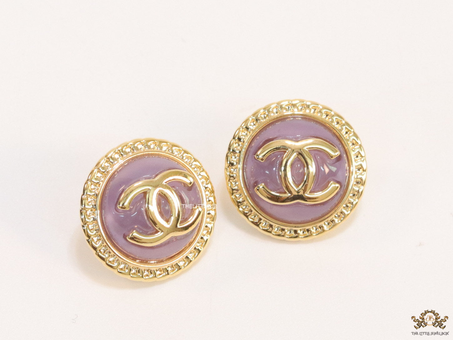 Twin C motif gold plated round studs on lilac acrylic base