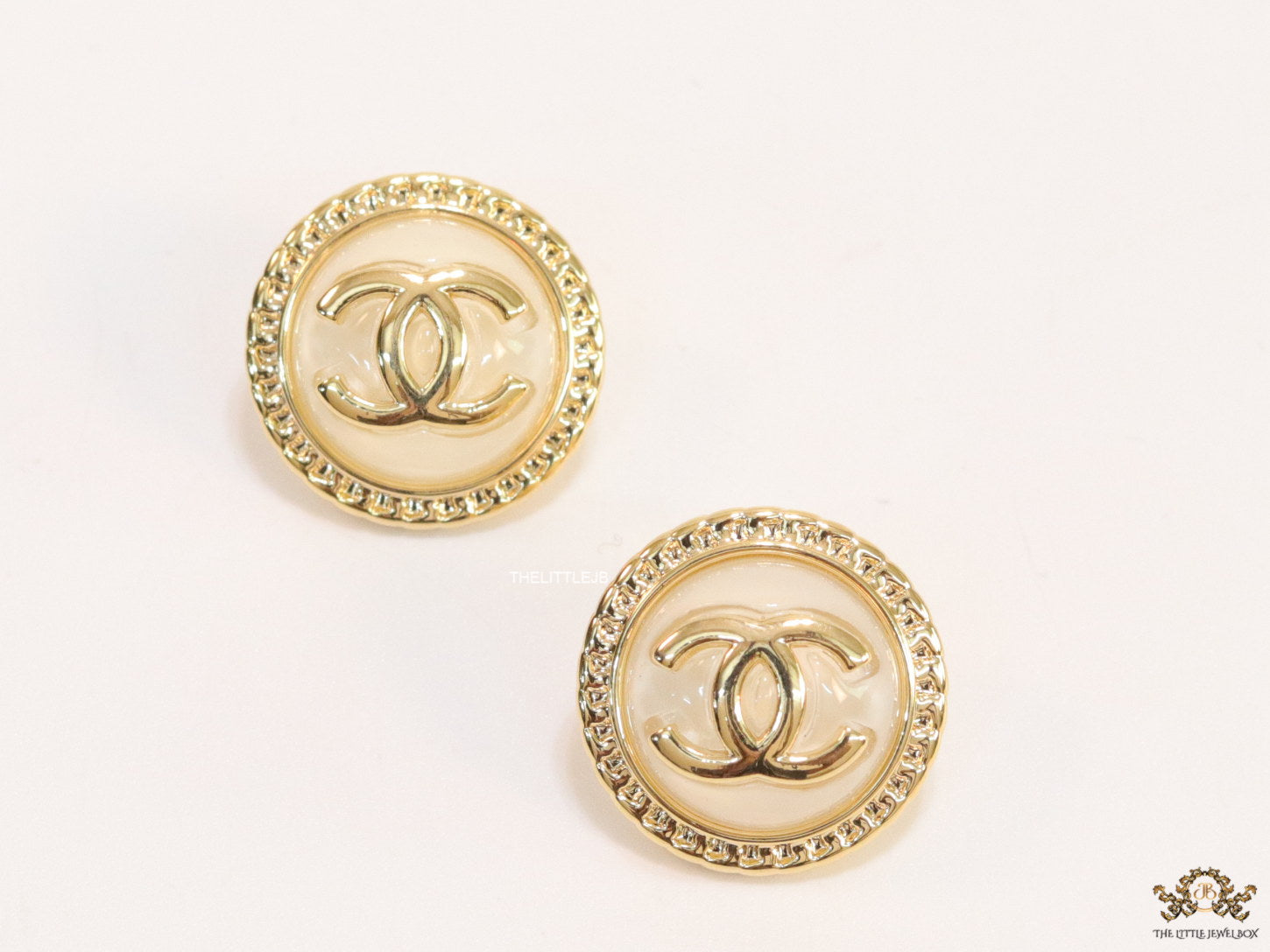Twin C motif gold plated round studs on pearly cream acrylic base