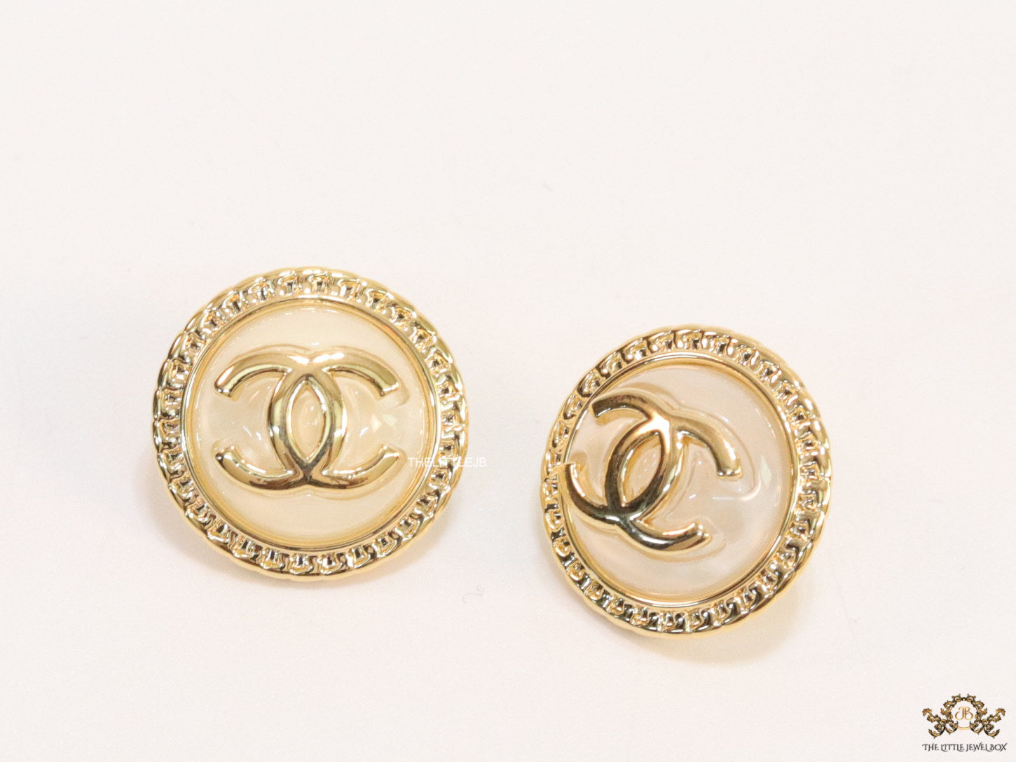 Twin C motif gold plated round studs on pearly cream acrylic base