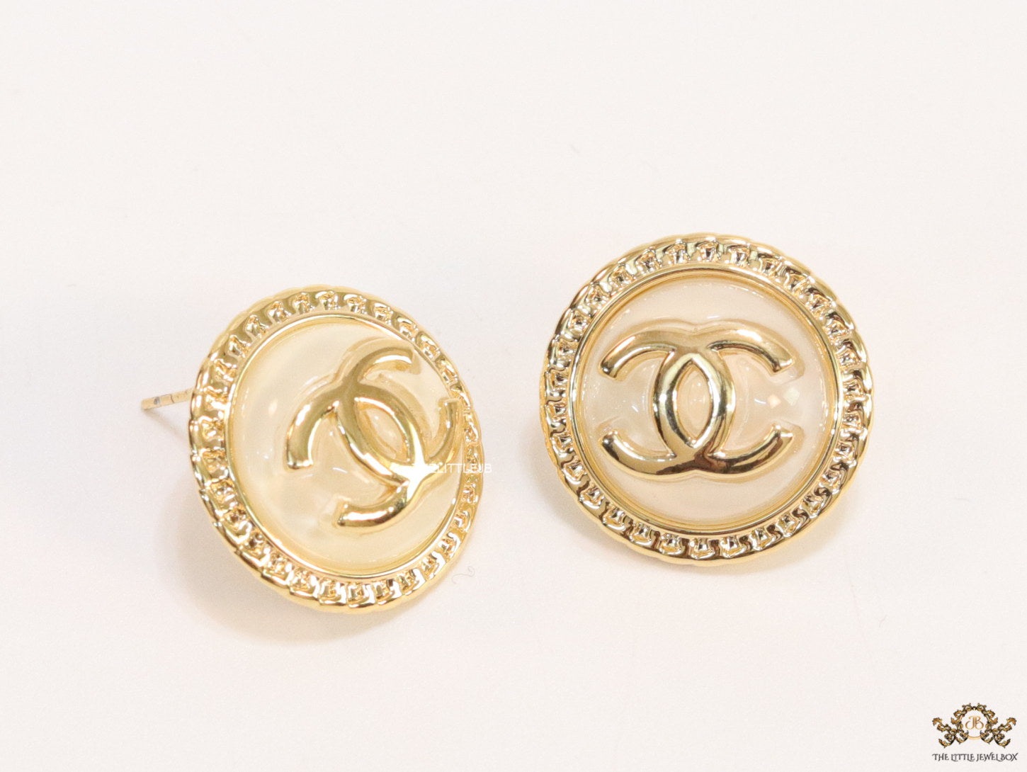 Twin C motif gold plated round studs on pearly cream acrylic base