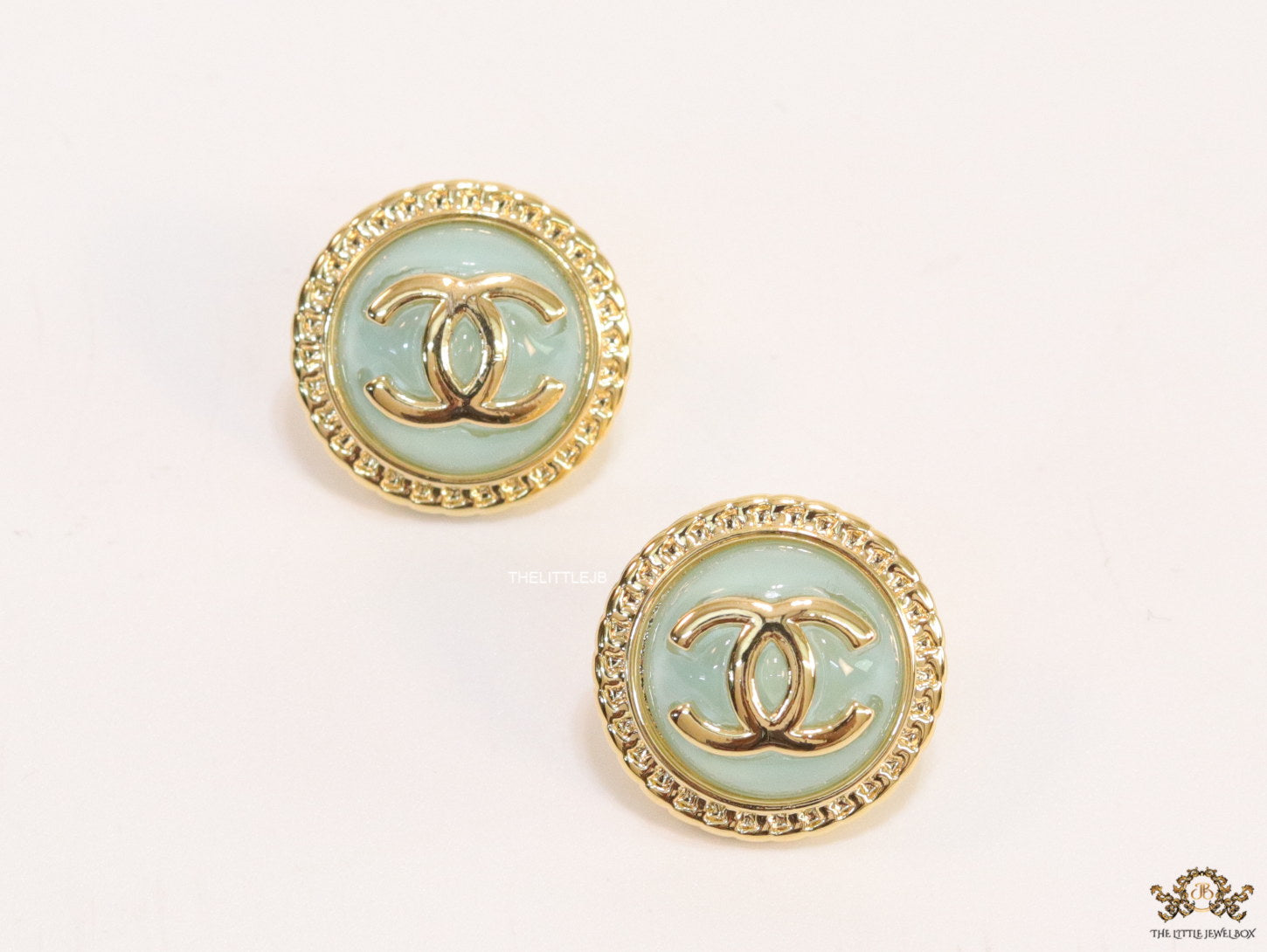 Twin C motif gold plated round studs on mint green acrylic base