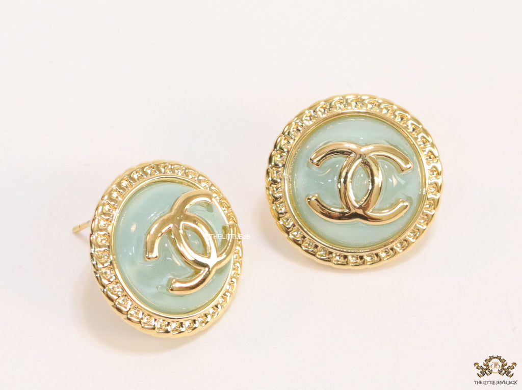 Twin C motif gold plated round studs on mint green acrylic base