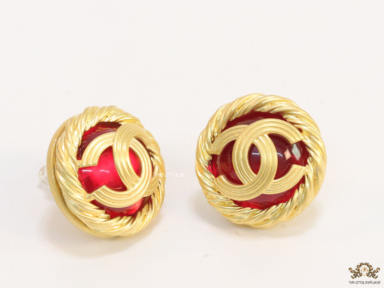 Twin C motif matt gold plated round studs on red base