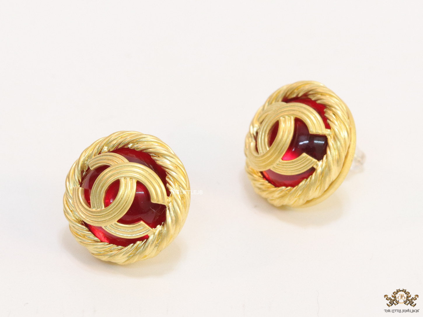 Twin C motif matt gold plated round studs on red base
