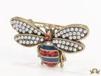 Antique gold finish bee brooch with white and red stones and blue details
