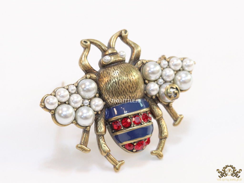 Antique gold finish double G bee brooch with blue details and white and red stones