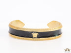 Band style black enamel bracelet with gold plated details and gold plated Medusa face motif