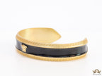 Band style black enamel bracelet with gold plated details and gold plated Medusa face motif