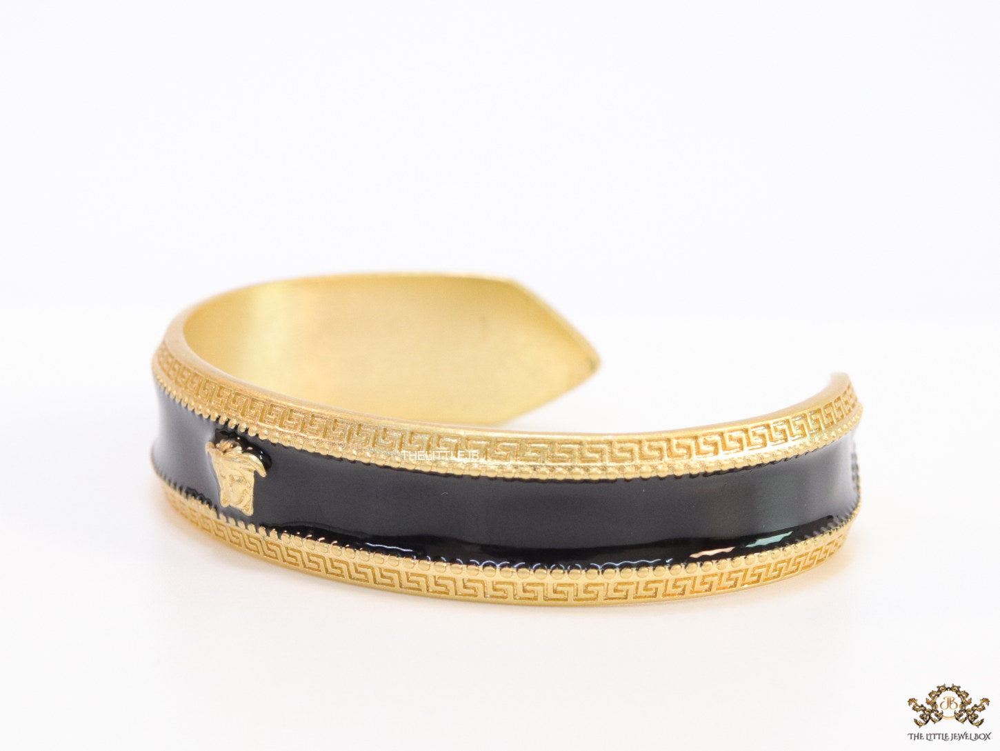 Band style black enamel bracelet with gold plated details and gold plated Medusa face motif
