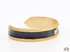 Band style black enamel bracelet with gold plated details and gold plated Medusa face motif