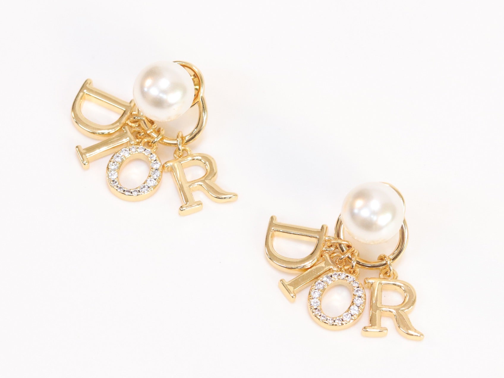 Alphabet CD dangling pearl studs in gold finish with CZ